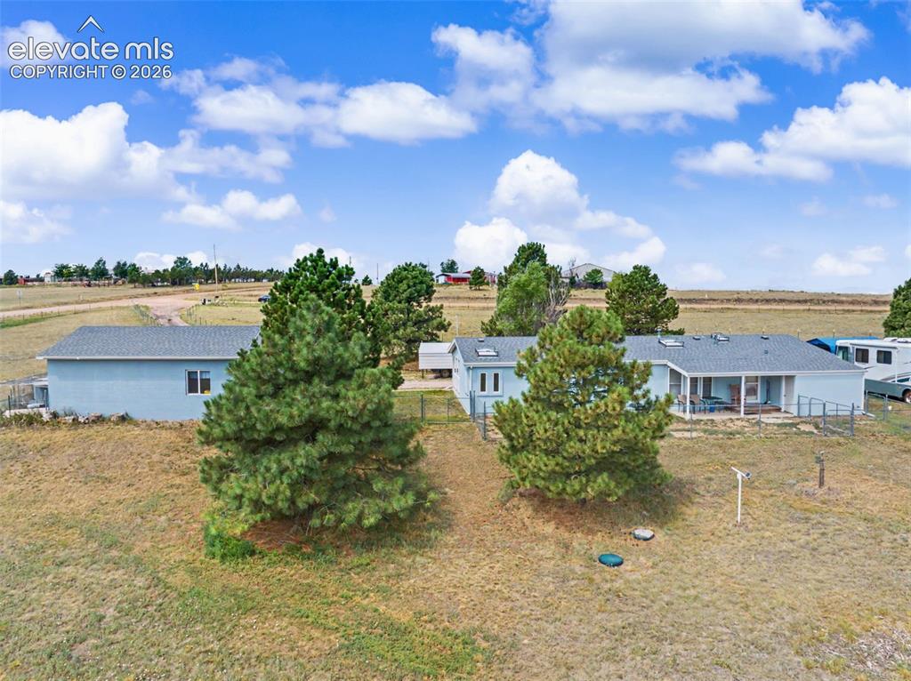 Image 33 of 38: Expansive property featuring a light blue exterior, a covered patio, mature
