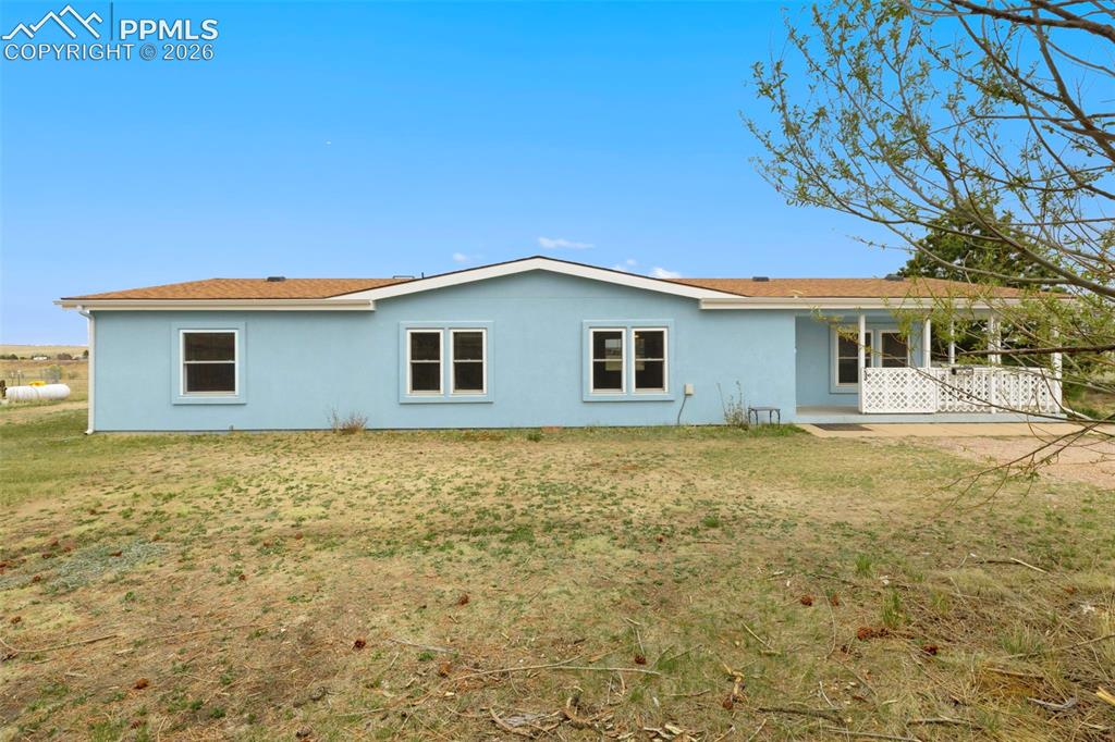 Image 34 of 38: Light blue exterior featuring multiple windows and a covered porch with whi