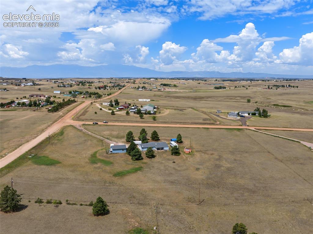 Image 35 of 38: Expansive rural landscape featuring a property with multiple structures, ma