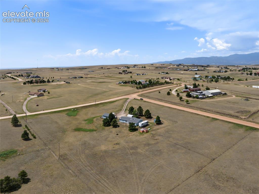 Image 36 of 38: Expansive rural landscape featuring a property with multiple structures, ma