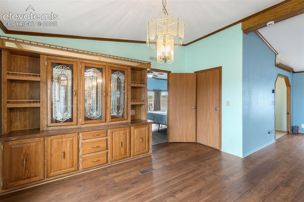 Image 7 of 38: Built-in wood-finish cabinetry featuring decorative glass door inserts and