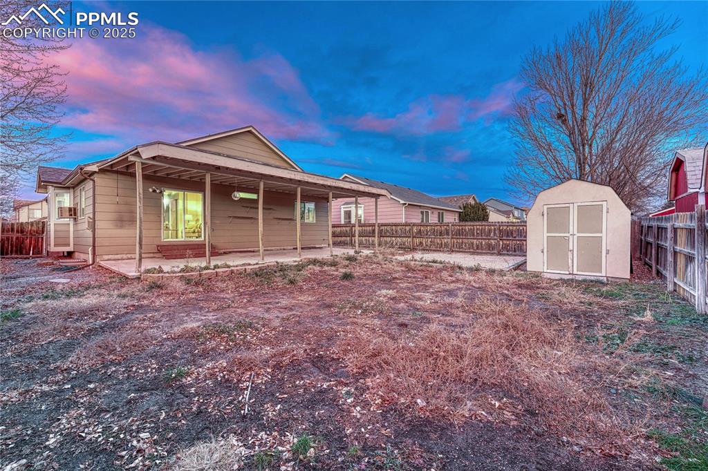 Image 12 of 47: Backyard with covered back patio and storage shed