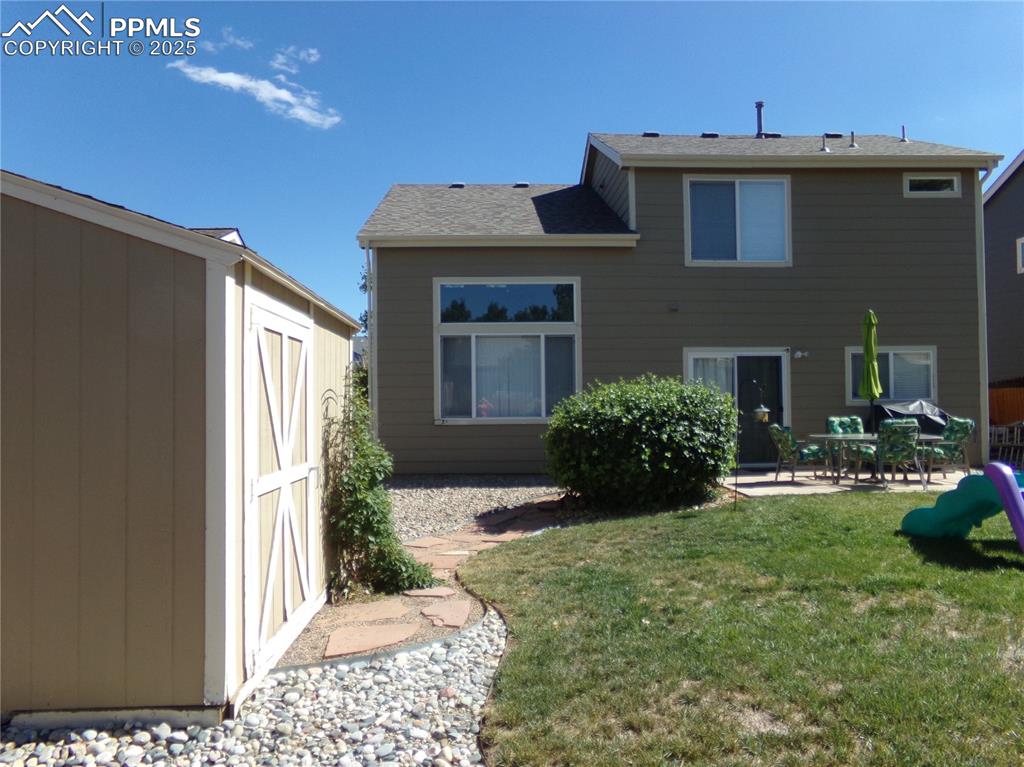 Image 20 of 22: Back of property with a patio, a storage unit, and a yard