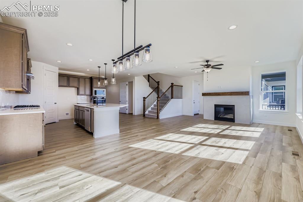 Image 10 of 28: Kitchen featuring open floor plan, a glass covered fireplace, pendant light