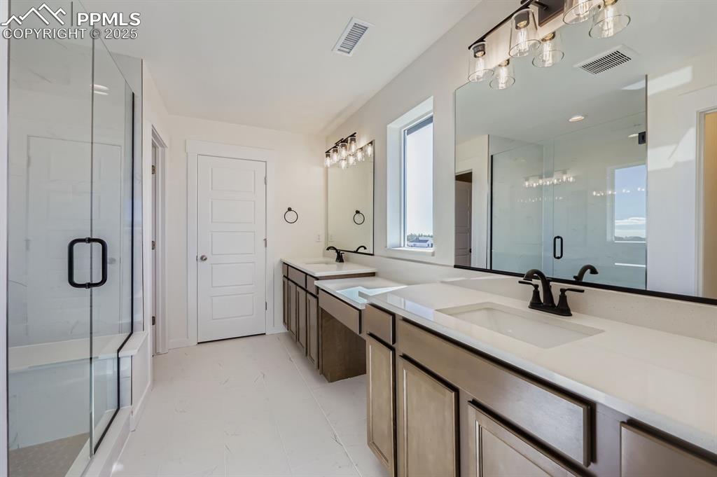 Image 14 of 28: Bathroom featuring double vanity and a stall shower