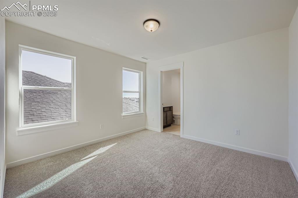 Image 17 of 28: Unfurnished bedroom with light colored carpet and connected bathroom
