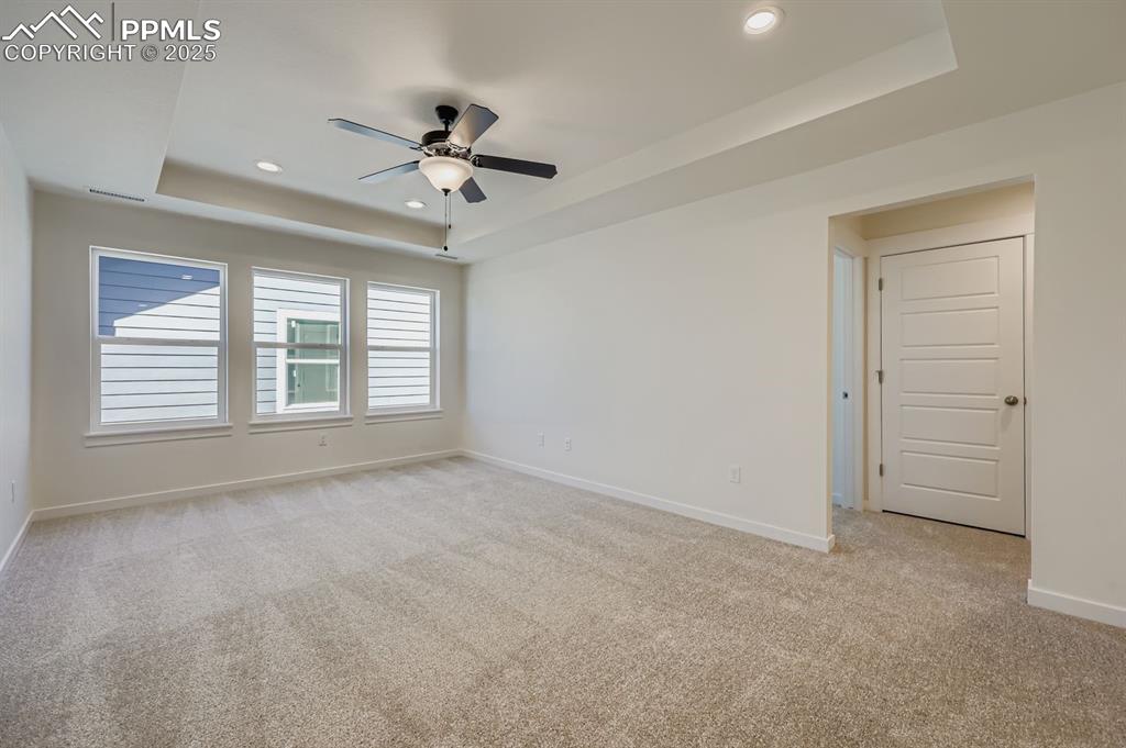 Image 22 of 28: Spare room featuring a raised ceiling, light carpet, recessed lighting, and