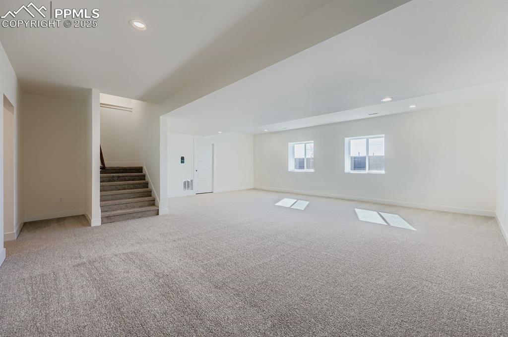 Image 23 of 28: Below grade area with recessed lighting, light carpet, and stairway