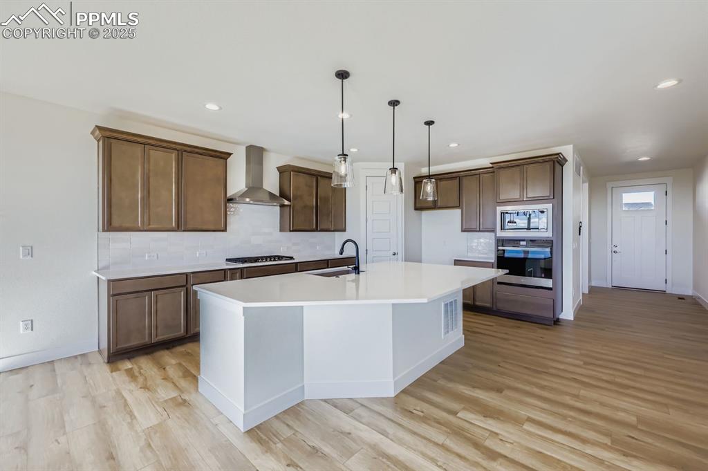 Image 9 of 28: Kitchen with backsplash, stainless steel appliances, decorative light fixtu