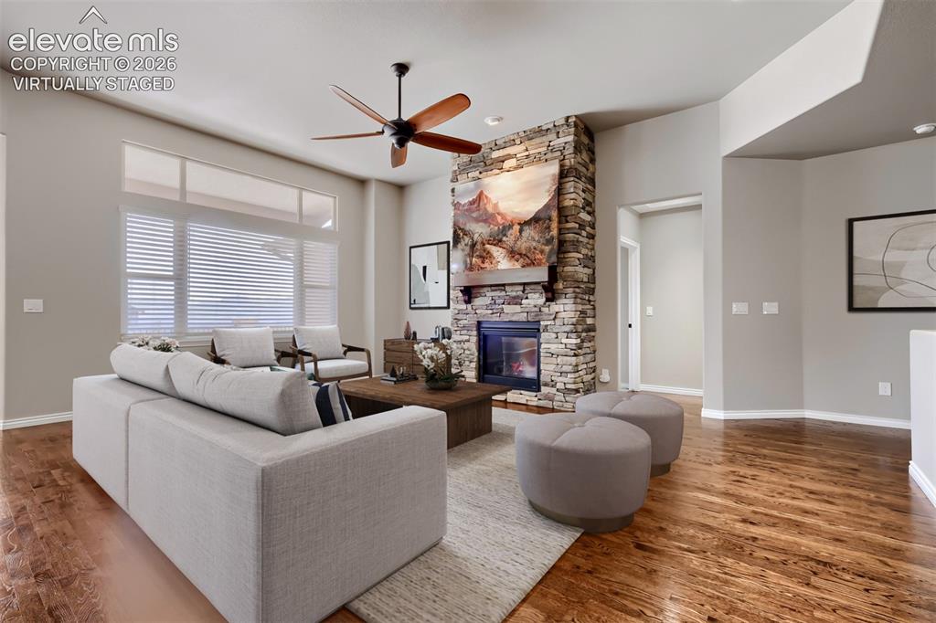 Image 6 of 50: Virtually staged living room with picture windows, stone fireplace, open co