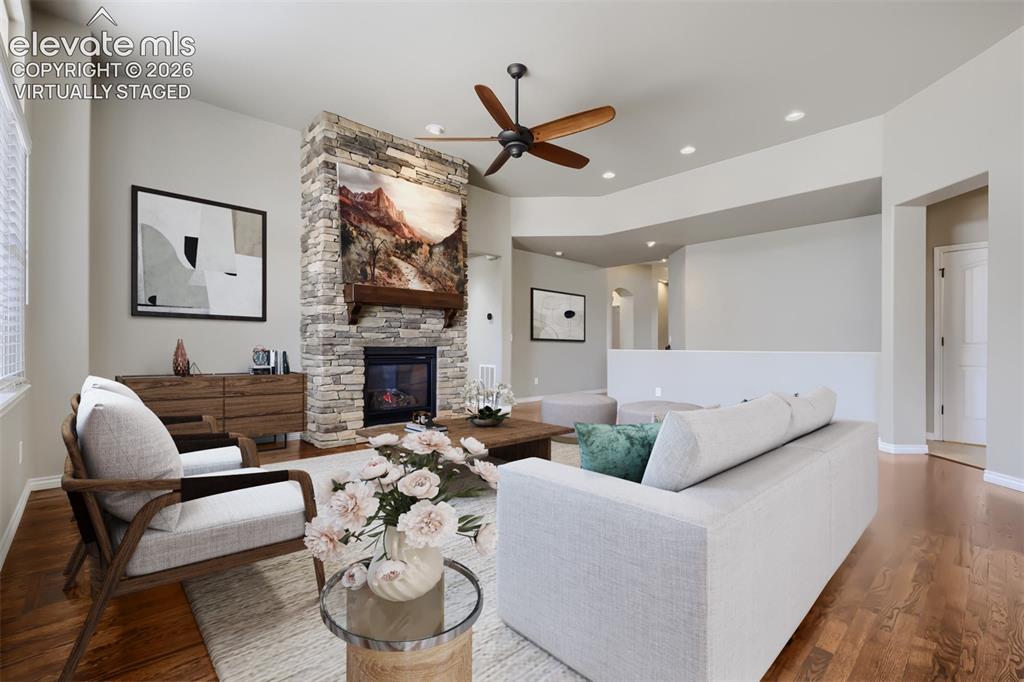 Image 8 of 50: Virtually staged living room with picture windows, stone fireplace, open co