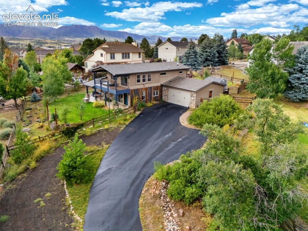 Caption: Expansive property featuring a paved driveway, mature trees, and a mountain backdrop
