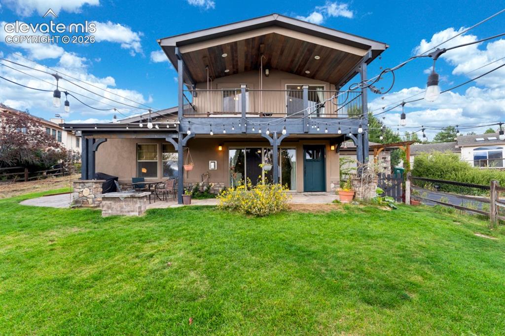 Image 10 of 50: Two-story exterior with a ground-level patio featuring a built-in stone fir