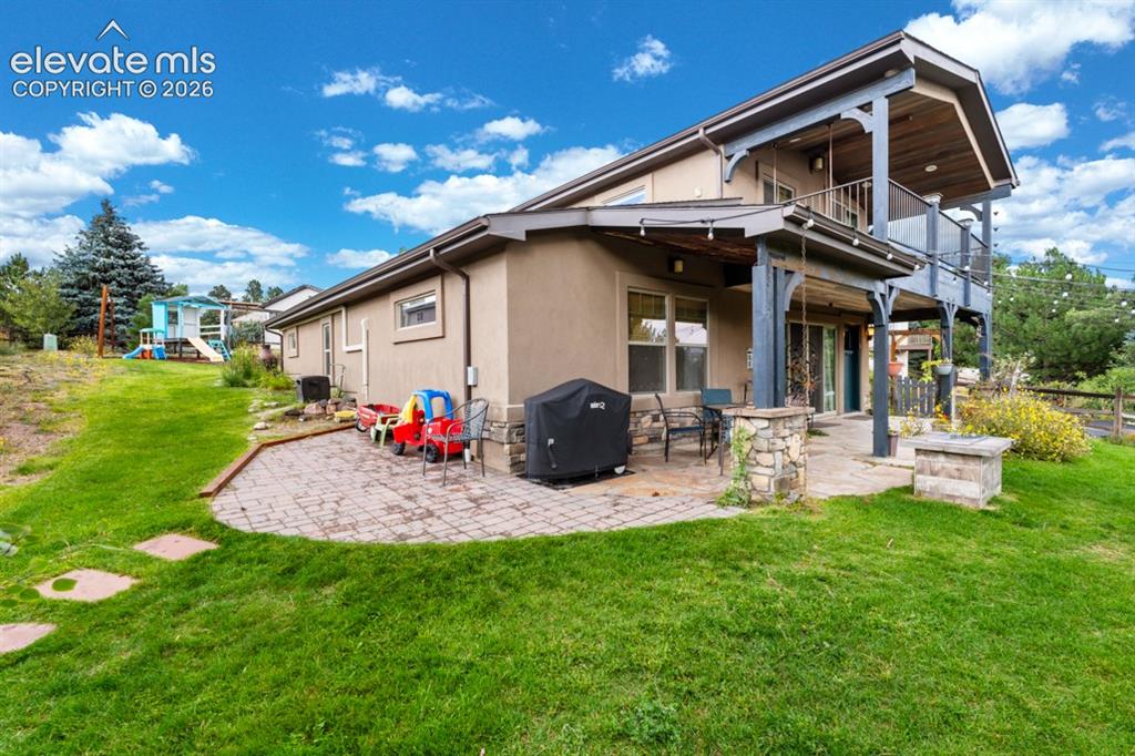 Image 11 of 50: Stucco exterior with stone accents, a multi-level deck, a covered patio, an