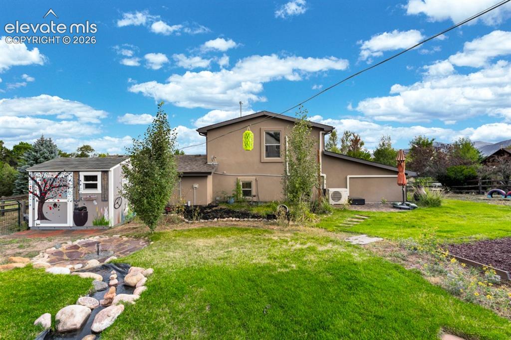 Image 12 of 50: Spacious backyard featuring a manicured lawn, a decorative dry creek bed, a