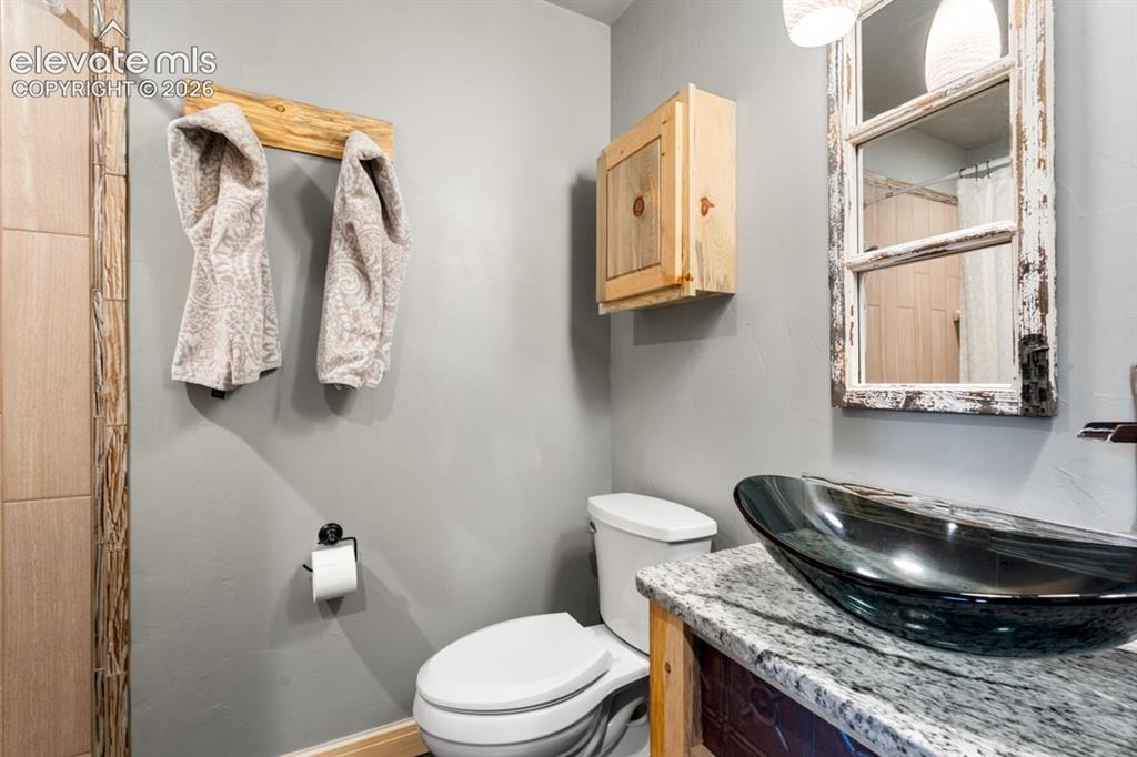 Image 14 of 50: Vessel sink with a granite countertop, rustic vanity, and a wooden wall cab