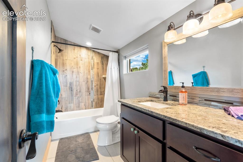 Image 16 of 50: Vanity with a granite-style countertop, undermount sink, and dark wood-fini