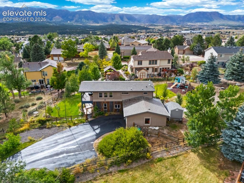 Image 2 of 50: Expansive property featuring a paved driveway, mature trees, and a mountain