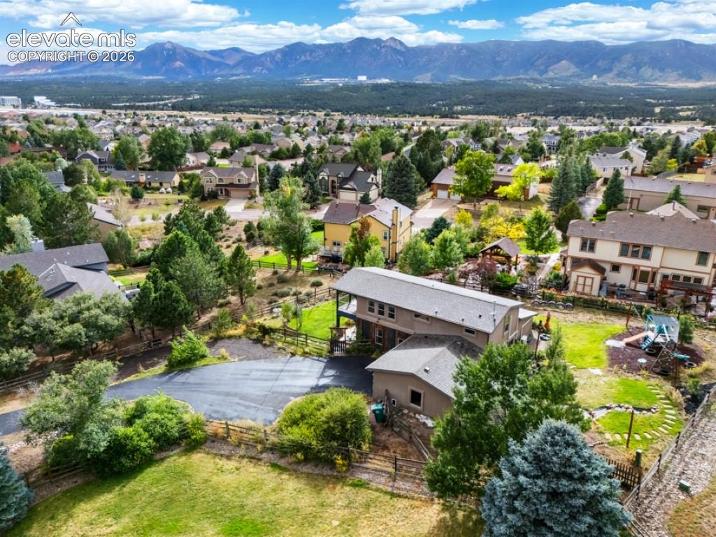 Image 3 of 50: Property featuring a paved driveway, multiple mature trees, and a wooden fe