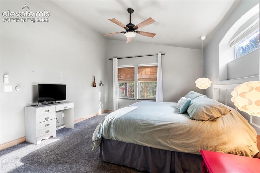 Image 31 of 50: Vaulted ceiling, ceiling fan, carpet flooring, arched window, and rectangul
