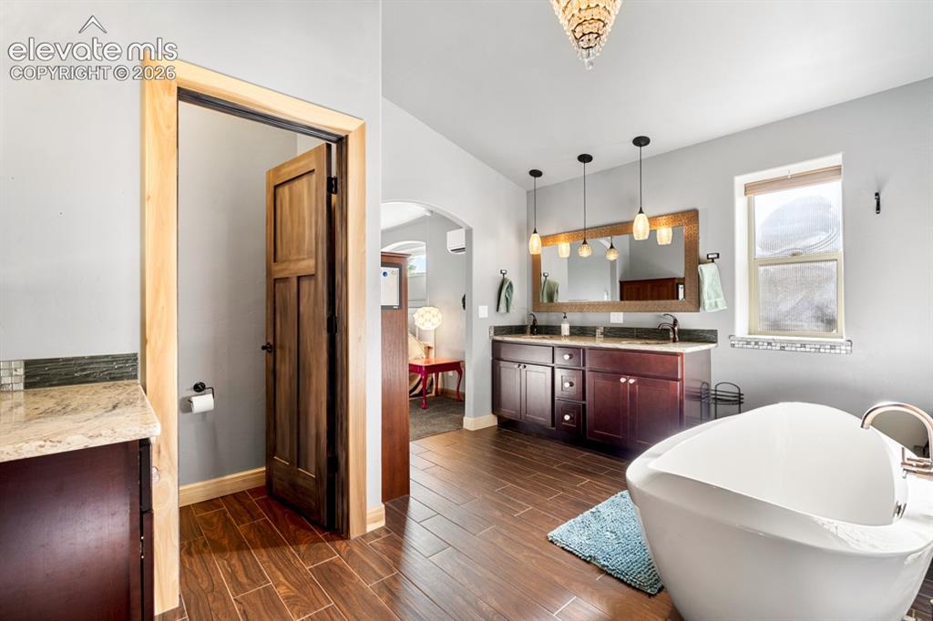 Image 35 of 50: Freestanding soaking tub, wood-finish flooring, dual vanity with undermount