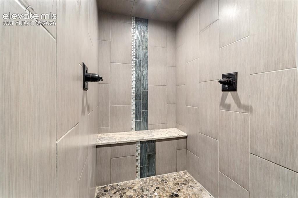 Image 37 of 50: Walk-in shower featuring large format tile, a decorative vertical accent ti