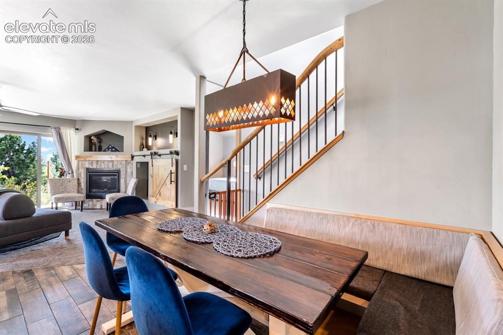 Image 45 of 50: Built-in dining bench, wood-finish flooring, stone-surround fireplace, barn