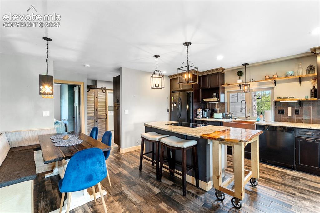 Image 49 of 50: Open-concept kitchen and dining area featuring wood-finish flooring, dark w