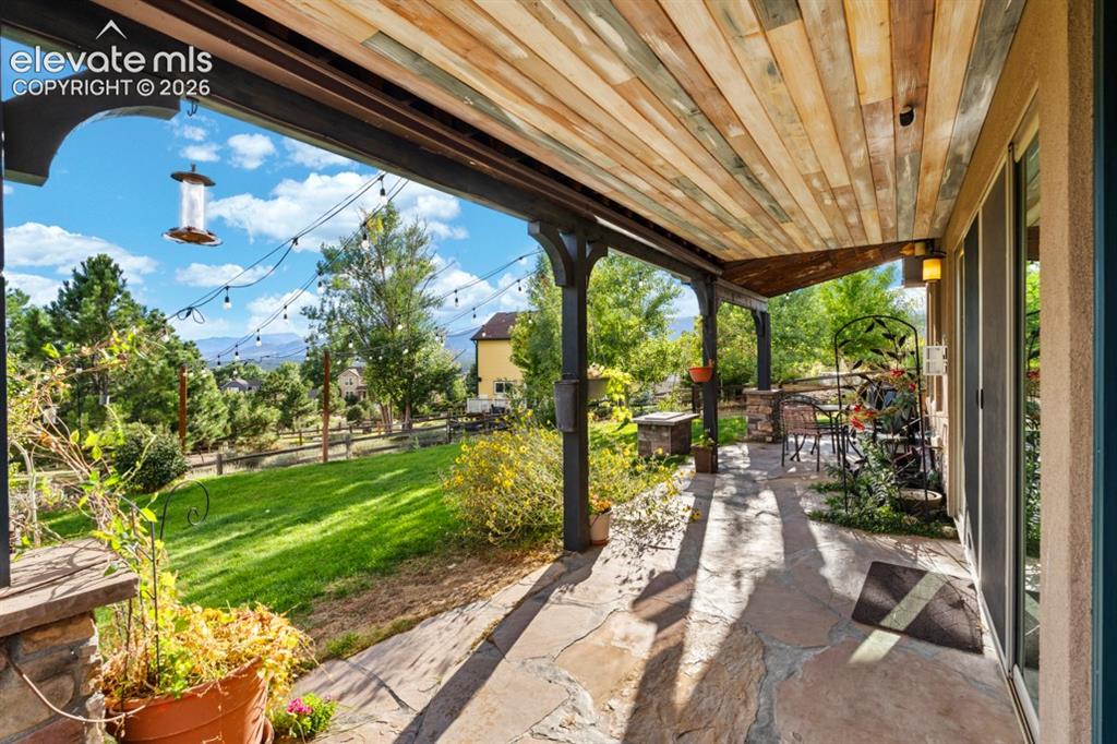 Image 50 of 50: Covered patio with a wood-plank ceiling, flagstone flooring, and stone-clad