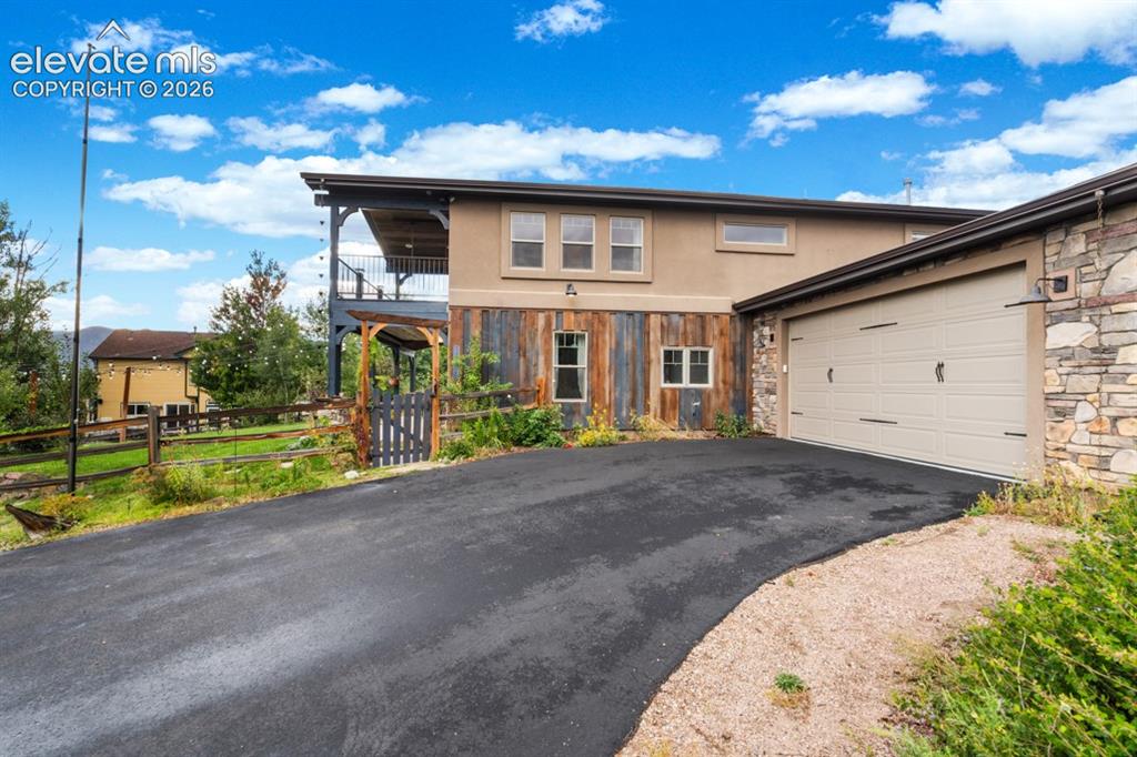 Image 9 of 50: Exterior featuring a two-car garage, stone and stucco siding, and a second-