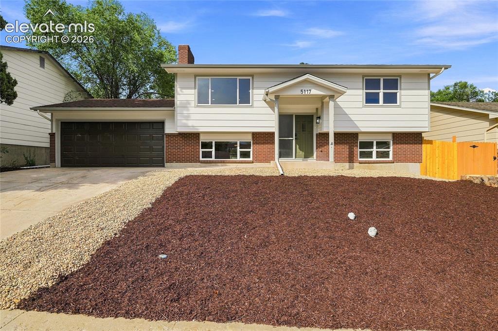 Image 1 of 30: Split-level residence featuring a brick and siding exterior, attached garag
