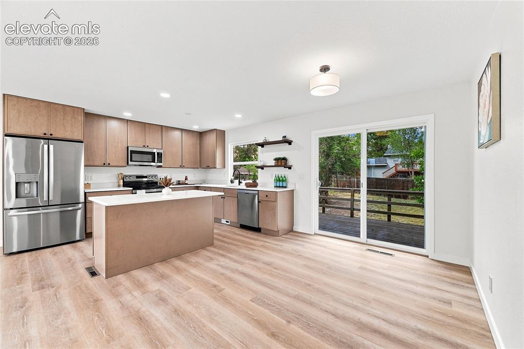 Image 2 of 30: Open-concept kitchen featuring wood-finish flooring, a kitchen island with