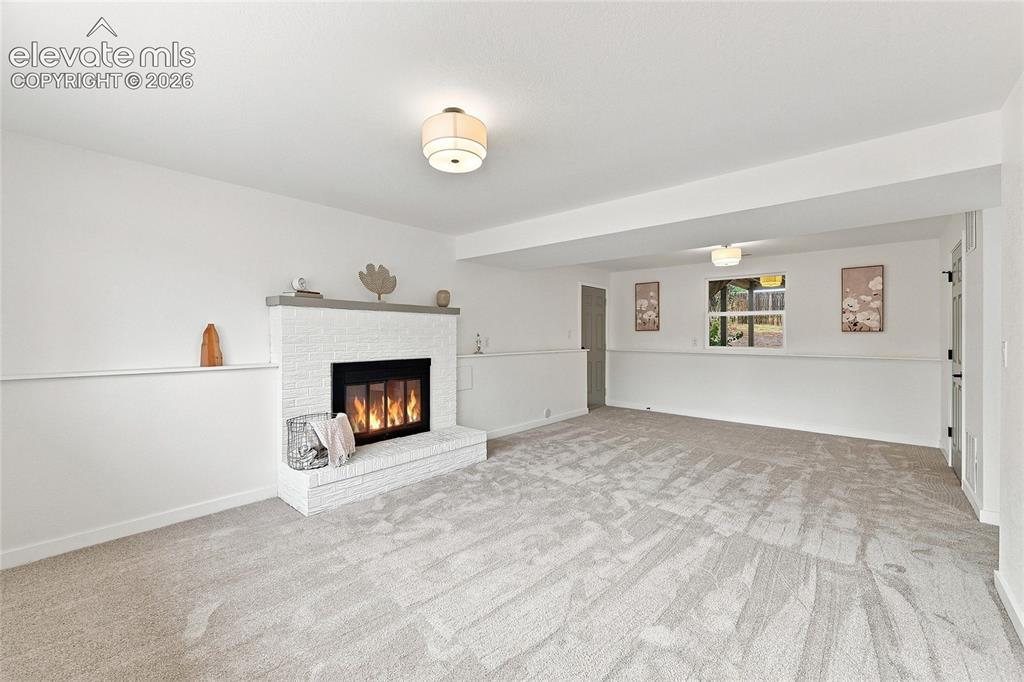 Image 4 of 30: White brick fireplace with a stone mantel, recessed lighting, and neutral-t