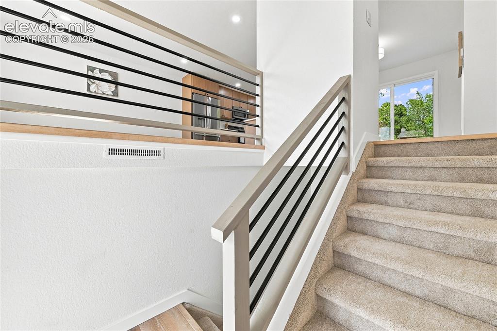 Image 5 of 30: Carpeted staircase with light wood-finish railings and black horizontal bal