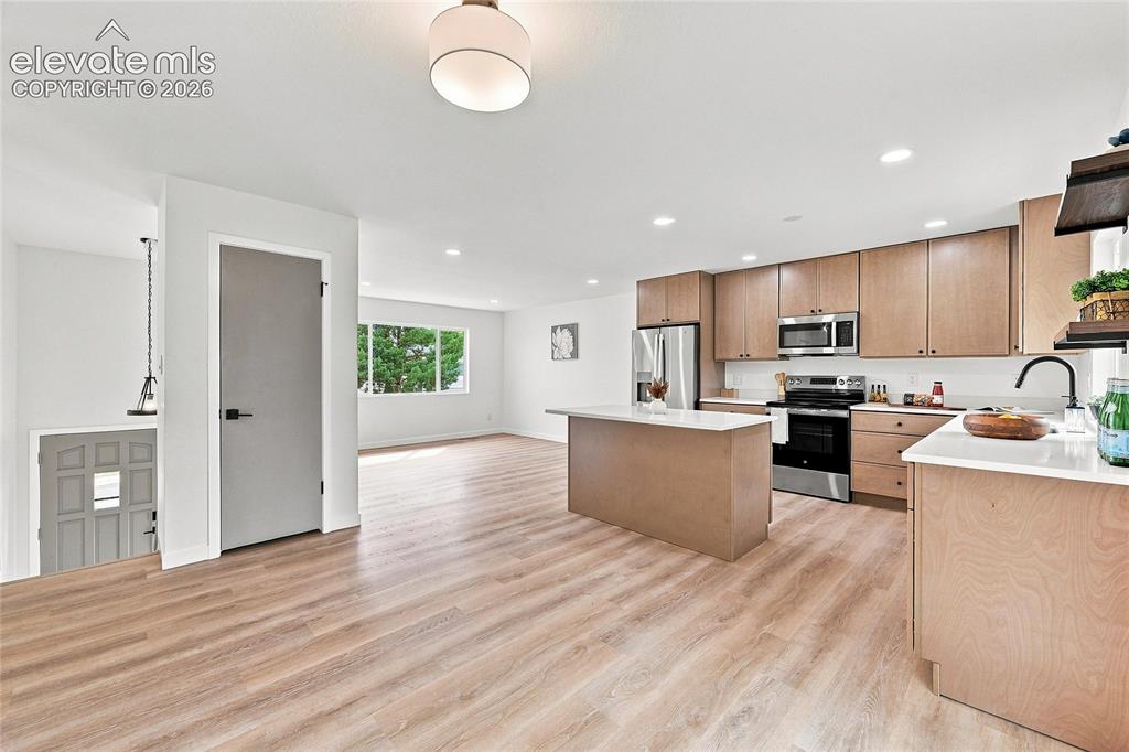 Image 6 of 30: Open-concept layout featuring wood-finish flooring, a kitchen island with a