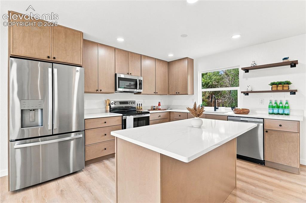Image 7 of 30: Contemporary kitchen featuring light wood-finish cabinetry, stainless steel