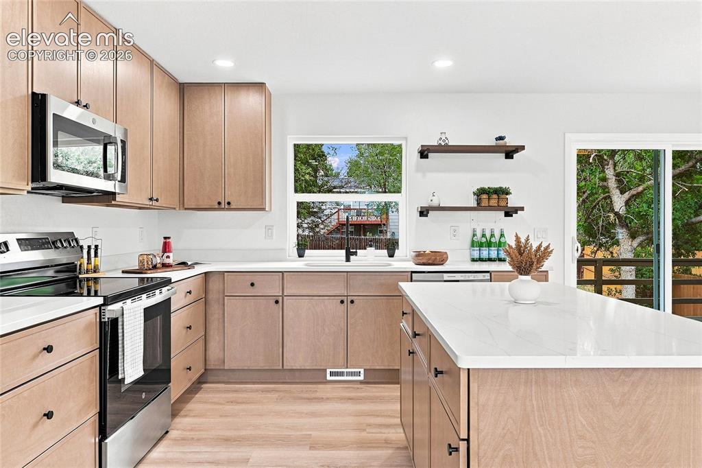 Image 8 of 30: Kitchen featuring wood-finish cabinetry, stainless steel appliances, a cent