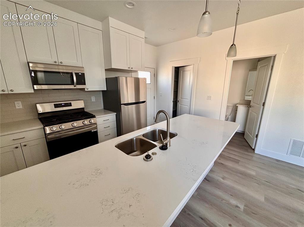 Image 11 of 21: Kitchen featuring a spacious island with dual stainless steel sinks and a g