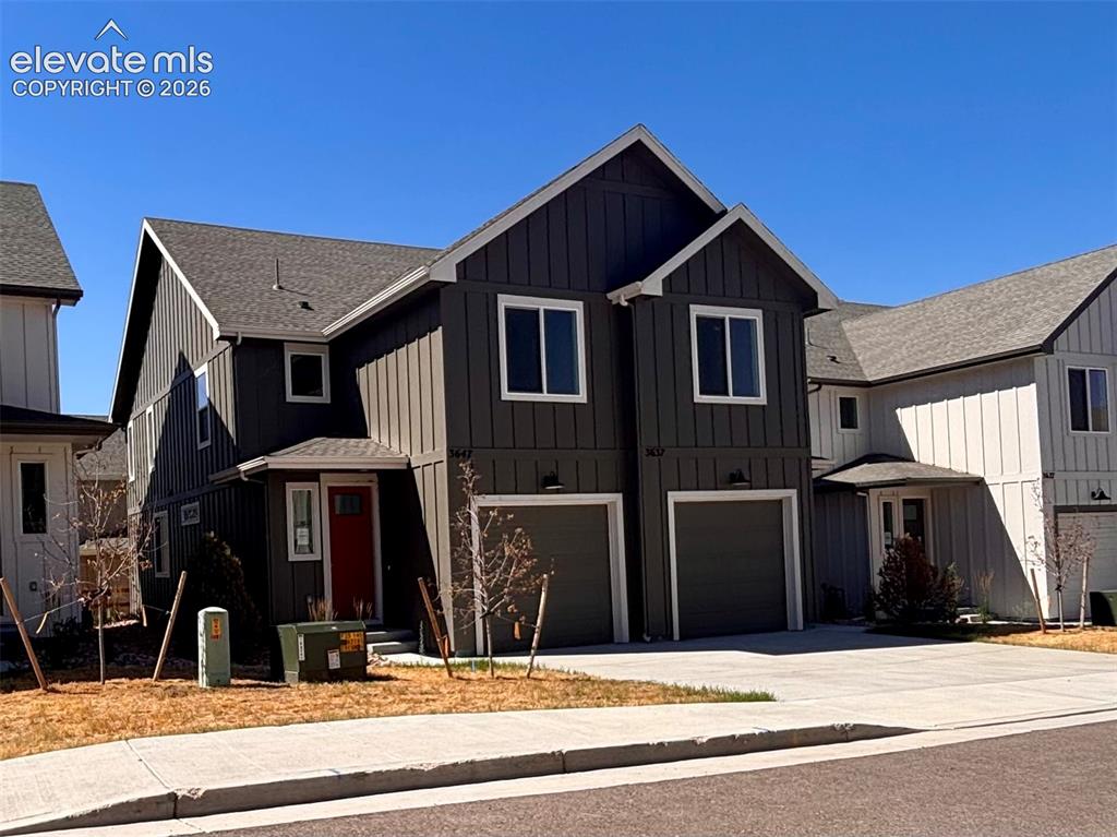 Image 2 of 21: Contemporary duplex with dark gray vertical siding, white trim accents, and