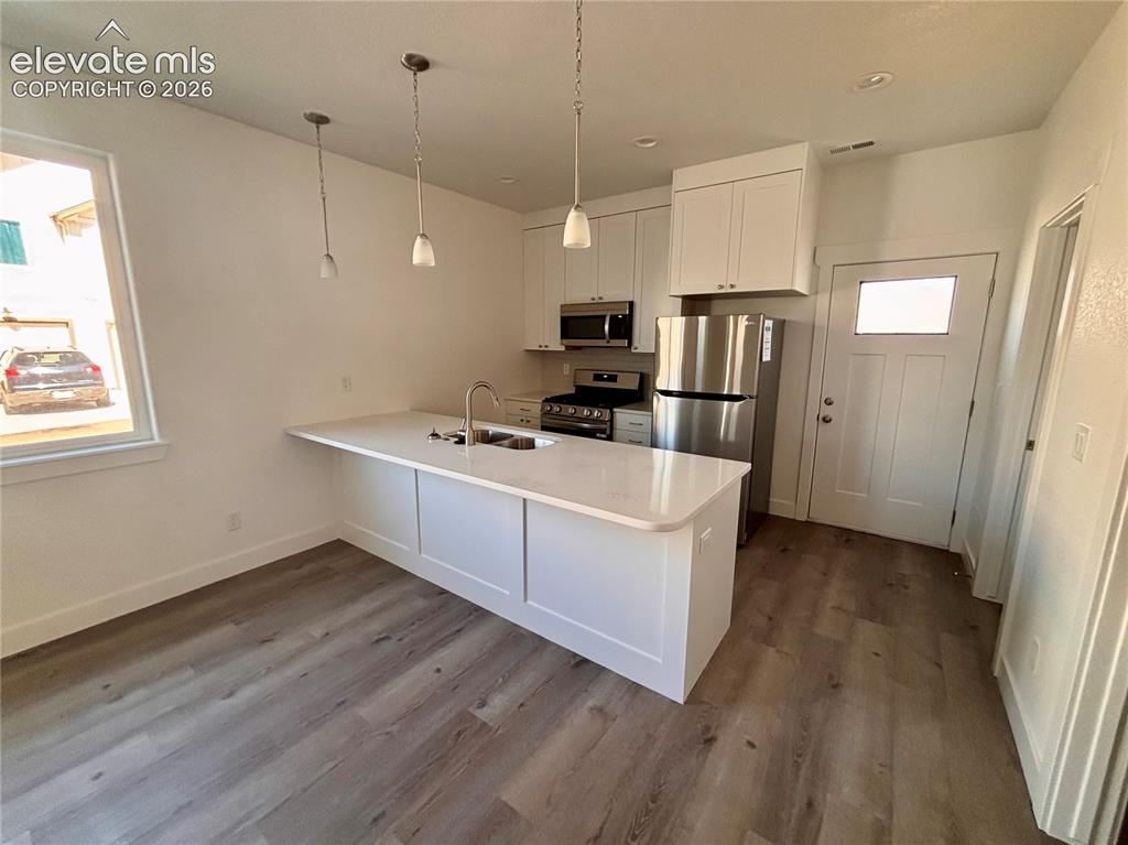 Image 5 of 21: Kitchen featuring a peninsula with a white countertop and a stainless steel