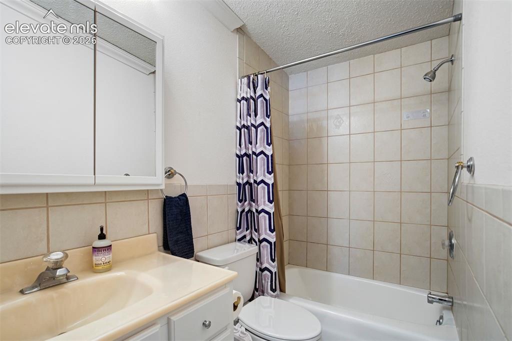 Image 27 of 50: Functional full bath with tub/shower combination and extended tile detail.