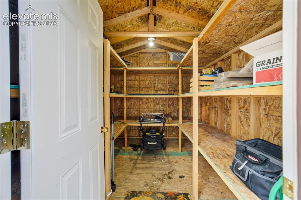 Image 44 of 50: Shed has ample shelving and electricity connected.