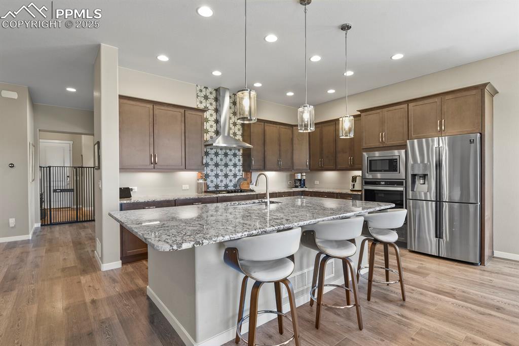 Image 12 of 50: Kitchen with stainless steel appliances, decorative light fixtures, light s