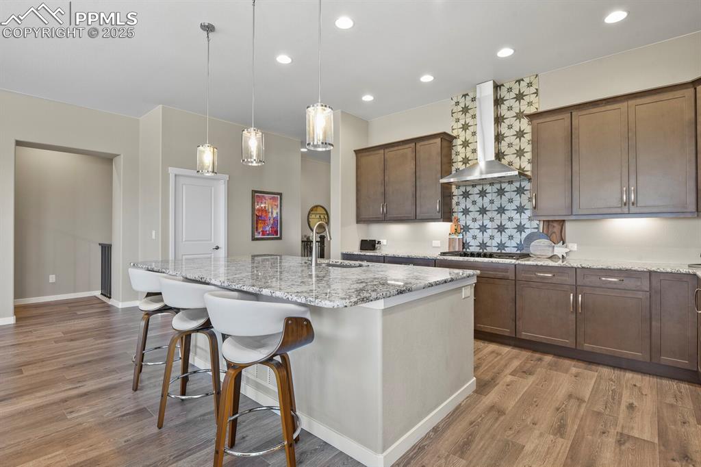Image 14 of 50: Kitchen with light stone counters, a kitchen breakfast bar, pendant lightin