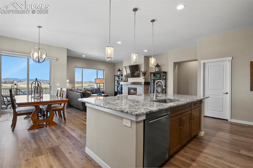 Image 15 of 50: Kitchen featuring a fireplace, light stone counters, pendant lighting, a ki
