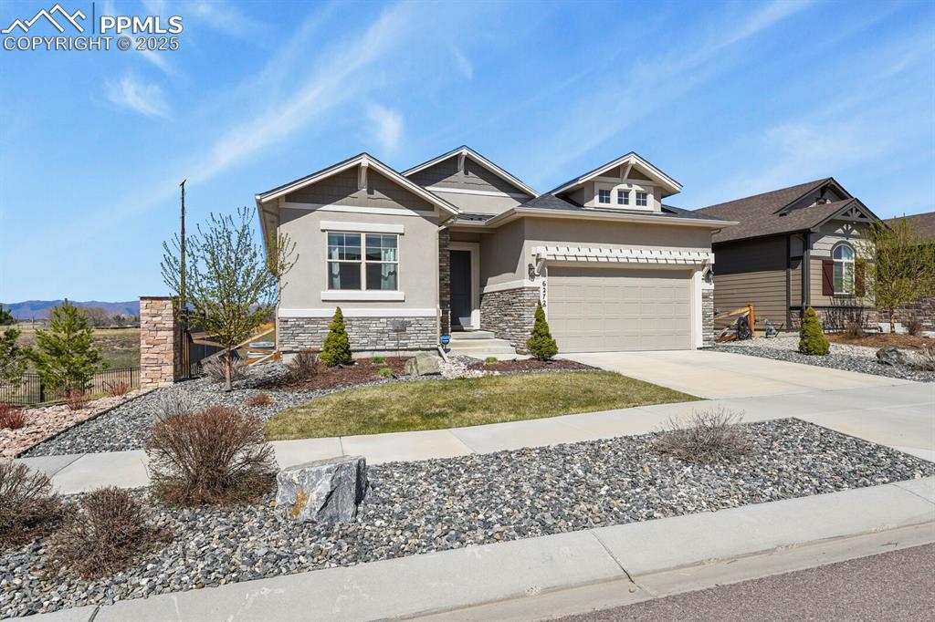 Image 2 of 50: Craftsman-style home featuring concrete driveway, stone siding, stucco sidi