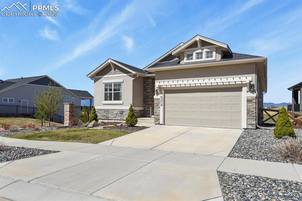 Image 3 of 50: Craftsman house with stucco siding, stone siding, concrete driveway, and an