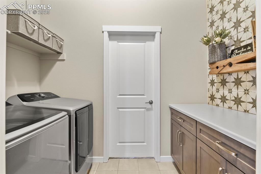 Image 30 of 50: Laundry room featuring cabinet space, light tile patterned flooring, and se