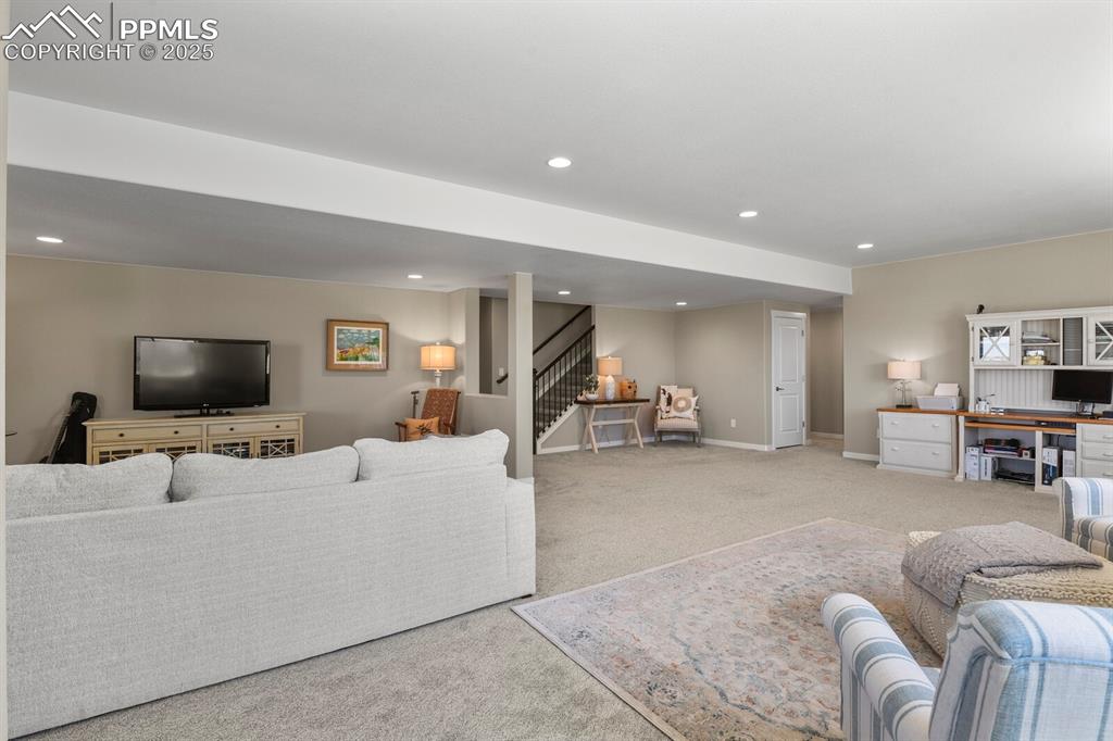 Image 36 of 50: Carpeted living room featuring a desk, stairs, and recessed lighting