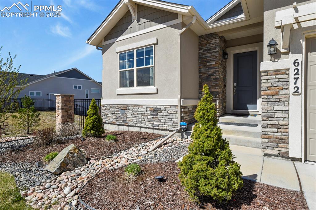 Image 4 of 50: View of exterior entry with stone siding and stucco siding